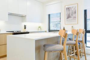 a kitchen with a white counter and three bar stools at Summit Central in Revelstoke