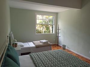 a bedroom with two beds and a window at Sítio Canto das Águas in Petrópolis