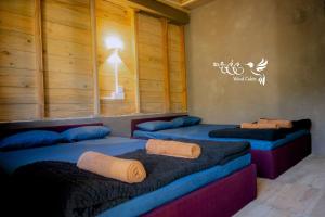 two beds in a room with wooden walls and windows at Kedella wood cabin in Nuwara Eliya