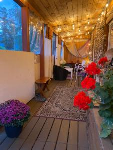 a porch with red flowers and a table and chairs at Rose Cottage Bed & Breakfast in Valemount