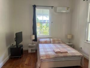 a bedroom with a bed and a television and a window at Gabba Beautiful rooms in Brisbane