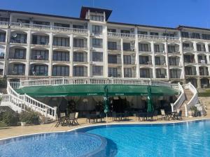 a hotel with a swimming pool in front of a building at Triumph Holiday Village in Sveti Vlas