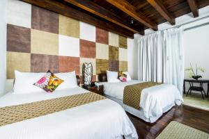 zwei Betten in einem Zimmer mit einer Schachbrettwand in der Unterkunft Colombe Hotel Boutique in Xalapa