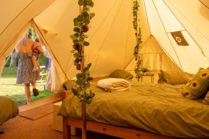 a woman standing in a tent with a bed at Aldwark Bridge Glamping - Aurora Tent in Aldwark