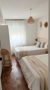 a bedroom with two beds and a chair and a chandelier at A beira do Mar in Bueu