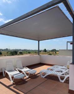 a patio with white chairs and a white canopy at Serenity Gelves in Gelves
