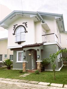 a white house with a gate and a balcony at Adorable Panglao Vacation House in Dauis