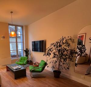 a living room with green chairs and a potted plant at Appartement de charme en plein cœur du centre historique - Parking Public Gratuit - in Avallon
