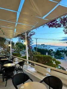 a patio with tables and chairs and a view of the ocean at Hotel Amaiià in Sarandë