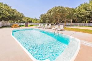a swimming pool with lounge chairs and a volley ball court at King BEEch - Southern Shores, 300 Yds to Beach, Ocean View, Pool, Hot Hub, Fenced Yard in Southern Shores
