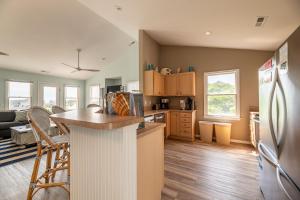a kitchen with a refrigerator and a counter top at King BEEch - Southern Shores, 300 Yds to Beach, Ocean View, Pool, Hot Hub, Fenced Yard in Southern Shores +58 photos