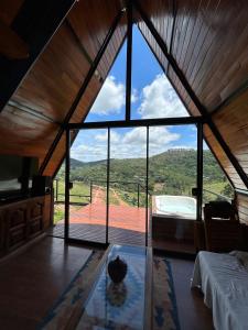 a room with a large window with a bed and a tub at Chalé Vale da Cachoeira in Três Rios
