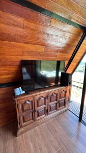 a large flat screen tv on a wooden wall at Chalé Vale da Cachoeira in Três Rios