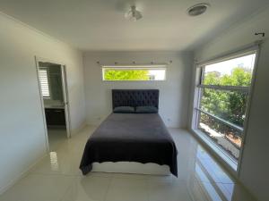 a bedroom with a bed and two windows at Master's bedroom in Mount Duneed in Mount Duneed