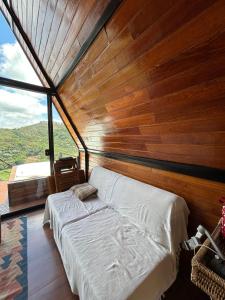 a bed in a room with a wooden wall at Chalé Vale da Cachoeira in Três Rios