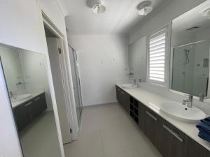 a white bathroom with two sinks and a mirror at Master's bedroom in Mount Duneed in Mount Duneed