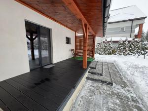 a house with a wooden deck in the snow at Klimatyczny Dom in Zamość