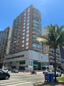 a tall building with a palm tree in front of it at Ocean flat in Vila Velha