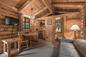 a log cabin living room with a table and a tv at Cowboy Village Resort in Jackson