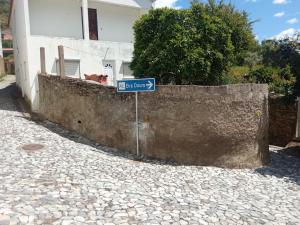 ein blaues Straßenschild vor einer Mauer in der Unterkunft EiraDouro Casa Amendoeira in Mós