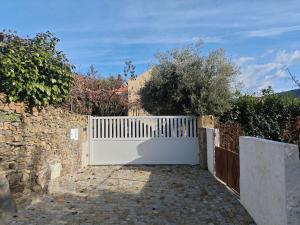 ein weißer Zaun vor einer Steinmauer in der Unterkunft EiraDouro Casa Amendoeira in Mós