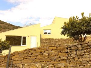 ein gelbes Haus hinter einer Steinmauer in der Unterkunft EiraDouro Casa Amendoeira in Mós