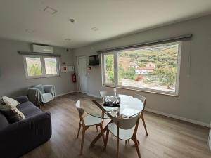 ein Wohnzimmer mit Tisch und Stühlen und einem Fenster in der Unterkunft EiraDouro Casa Amendoeira in Mós