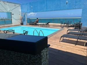 a swimming pool with chairs and a person in the background at Ocean flat in Vila Velha