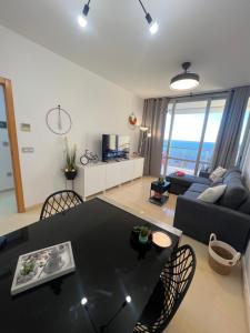 a living room with a black table and chairs at Coblanca 41-spectacular views-gym-heated pool-sauna-jacuzzi-wifi-3 minutes walk from the sear in Benidorm