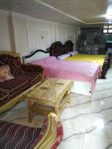 a room with two beds and a couch and chairs at راس البر المستشارين in ‘Izbat ash Sharāyid