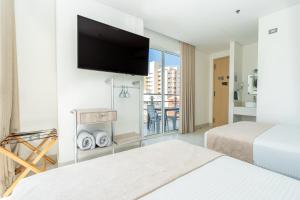 a hotel room with two beds and a flat screen tv at Hotel Marco Polo Rodadero in Santa Marta