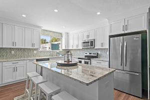 a kitchen with white cabinets and a large island with bar stools at Emerald Breeze in Destin