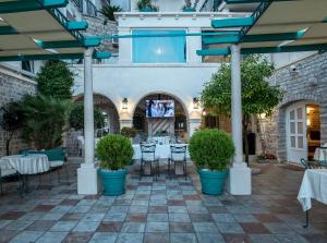 a patio with tables and chairs and potted plants at Hotel Azimut in Sveti Stefan
