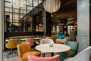 a restaurant with colorful chairs and tables and tablespaces at Motel One Hannover-Oper in Hannover