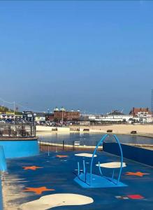 a swimming pool with two chairs and a beach at Silver stays, calm coastal stay , close to beach in Gorleston-on-Sea