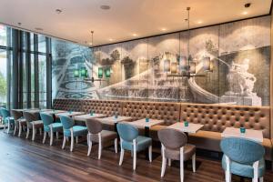 a dining room with tables and chairs and a mural at Motel One Wien-Hauptbahnhof in Vienna