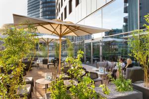 a patio with tables and chairs and an umbrella at Motel One Wien-Hauptbahnhof in Vienna