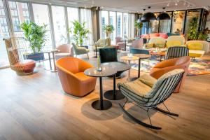 a lobby with chairs and tables and windows at Motel One Rotterdam in Rotterdam