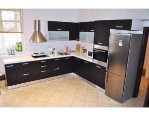 eine Küche mit schwarzen Schränken und einem Edelstahlkühlschrank in der Unterkunft Elegance on a Budget - Rooms for Rent in Sofia Center in Sofia