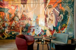 a room with chairs and tables in front of a mural at Motel One Graz in Graz +27 photos