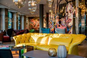 a yellow couch in a room with a table at Motel One Graz in Graz