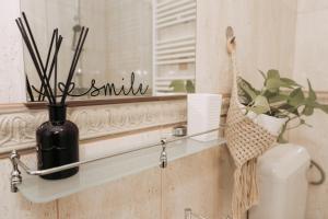 a bathroom with a mirror and a vase on a shelf at Apartament Andreas - centru, confort si relaxare in Arad