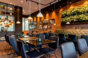 a restaurant with tables and chairs and plants at Motel One Salzburg-Süd in Salzburg