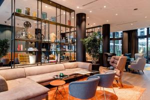 a lobby with a couch and tables and chairs at Motel One Köln-Messe in Cologne +26 photos