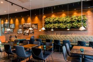 a restaurant with tables and chairs and plants on the wall at Motel One Salzburg-Süd in Salzburg