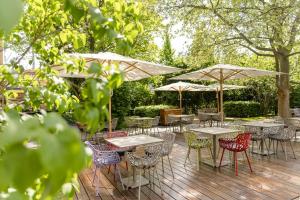 a wooden deck with tables and chairs and umbrellas at Motel One Wien-Prater in Vienna