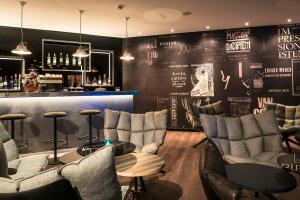 a restaurant with a bar with chairs and a table at Motel One Basel in Basel