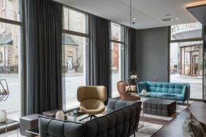 a living room with a couch and chairs and windows at Motel One Leipzig-Nikolaikirche in Leipzig +47 photos