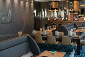 a restaurant with tables and chairs and a chandelier at Motel One Leipzig-Nikolaikirche in Leipzig