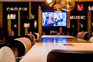a dining room with tables and chairs and a tv at Motel One Warsaw-Chopin in Warsaw +21 photos
